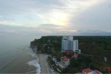 Aerial view of ocean coastline, beachfront condos, lush greenery, and cliffs at Playa Corona