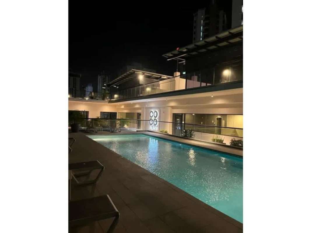 Night view of infinity pool with lounge chairs and cityscape at PH Coco Place Panama
