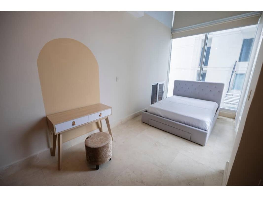 Bedroom with gray upholstered bed, floor to ceiling windows, ocean view in Punta Pacifica Panama