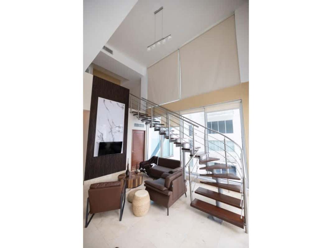 Double-height living room with floating staircase and marble accent wall in PH Ocean Club Punta Pacifica Panama