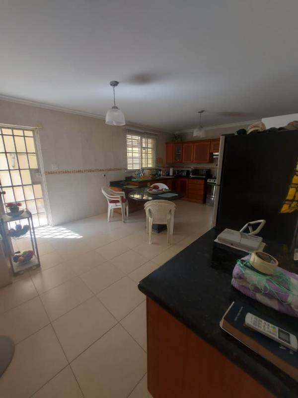Traditional kitchen with granite counters, wooden cabinets, dining area and large window in Panama house