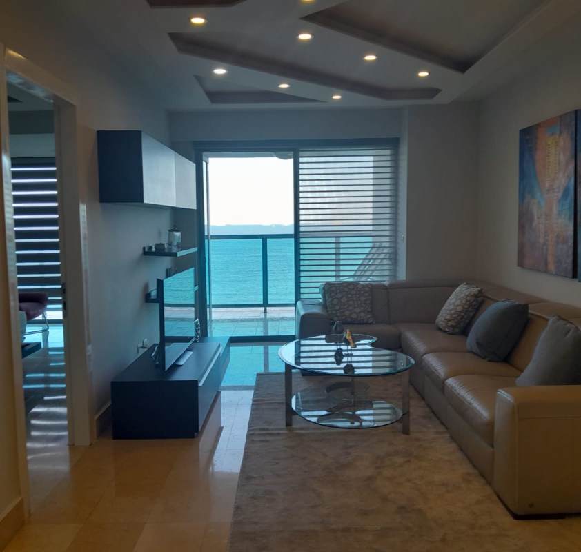 Furnished living room with sectional sofa and access to balcony overlooking ocean at PH Yoo Panama