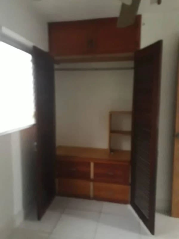 Bedroom closet with built-in drawers, hanging rod, and overhead cabinet in Edificio Concordia Panama