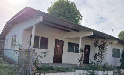 Exterior white single-story house with metal roof and garden fenced yard in Veraguas Panama
