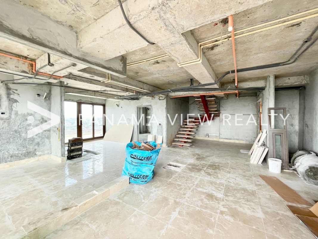 Unfinished marble tiled living space with large glass doors and panoramic views in luxury penthouse Santa Maria Panama
