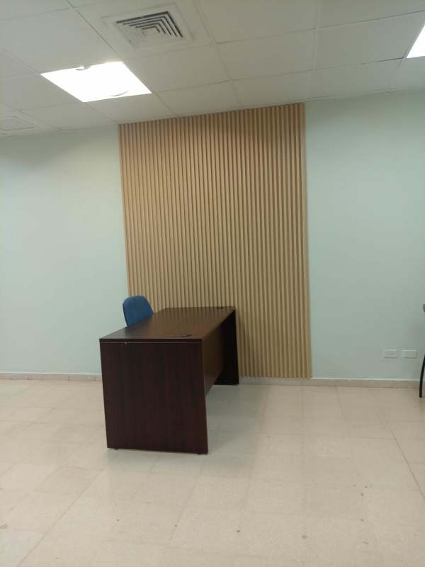 Office interior with wooden accent wall, blue chair and minimalist decor at PH BICSA Tower in Marbella business district
