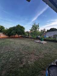 Fenced yard side angle with lawn and mature trees at family house in Aguadulce Coclé Panama