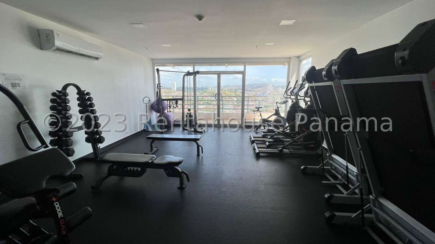 Compact kitchen with black cabinets, granite countertops, refrigerator, connected utility area at PH Vista Hermosa Panama City