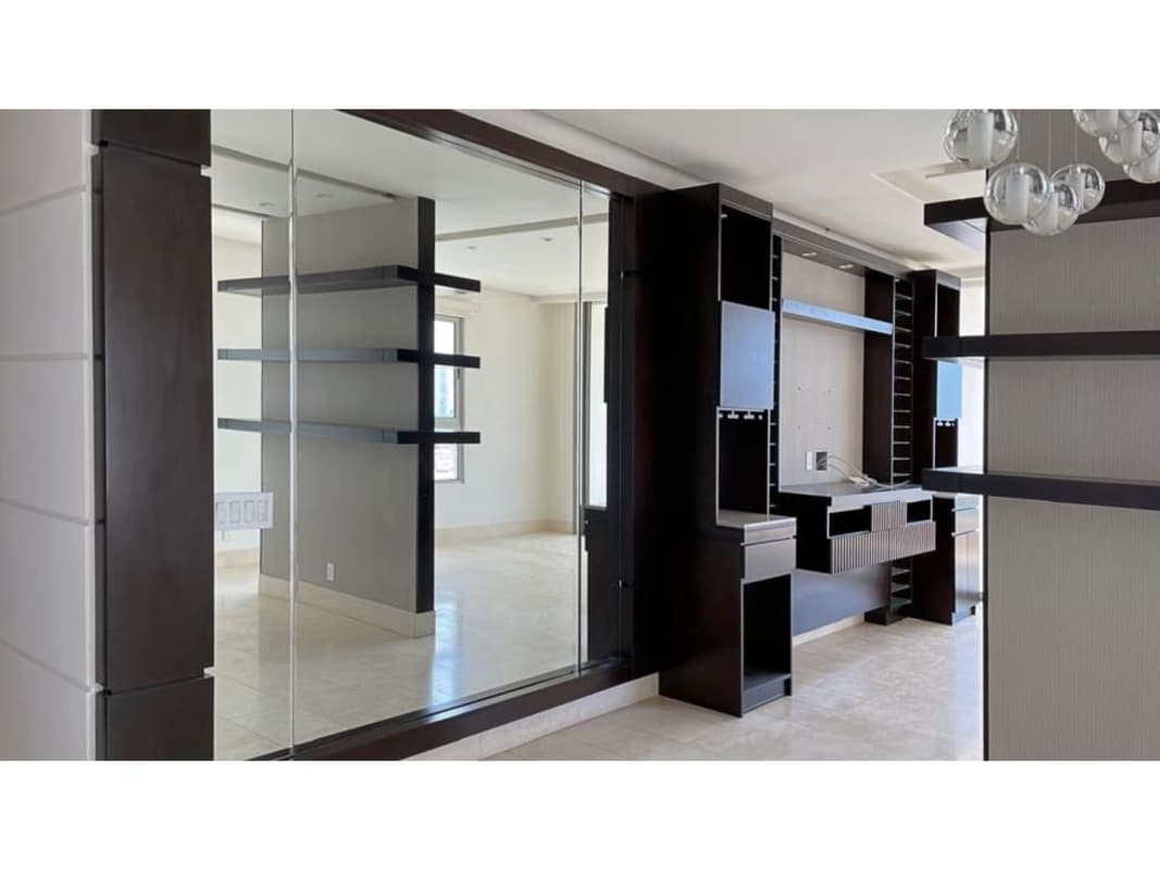 Contemporary living space with wall mirror, shelves, neutral tones at Greenview Residences Santa María Panama