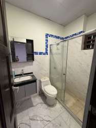 Elegant bathroom with glass shower, marble tiles, vanity with sink and mirror in San Antonio Las Lomas David