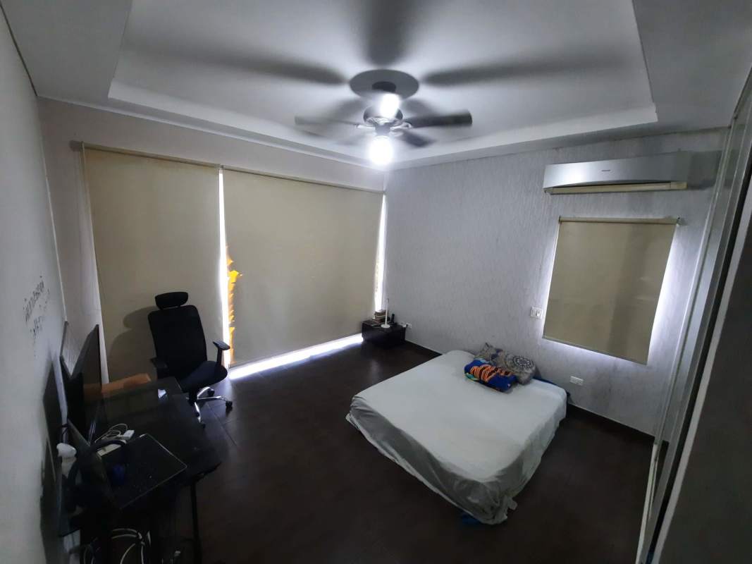 Modern minimalist bedroom with office space, roller shades and ceiling fan at Altos de Panamá