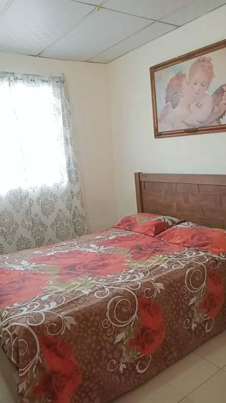 Room with floral bedspread wooden headboard tiled floors window patterned curtains Tocumen