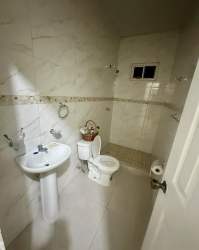 Traditional bathroom with pedestal sink, tile walls and window in Las Brisas David Panama house rental