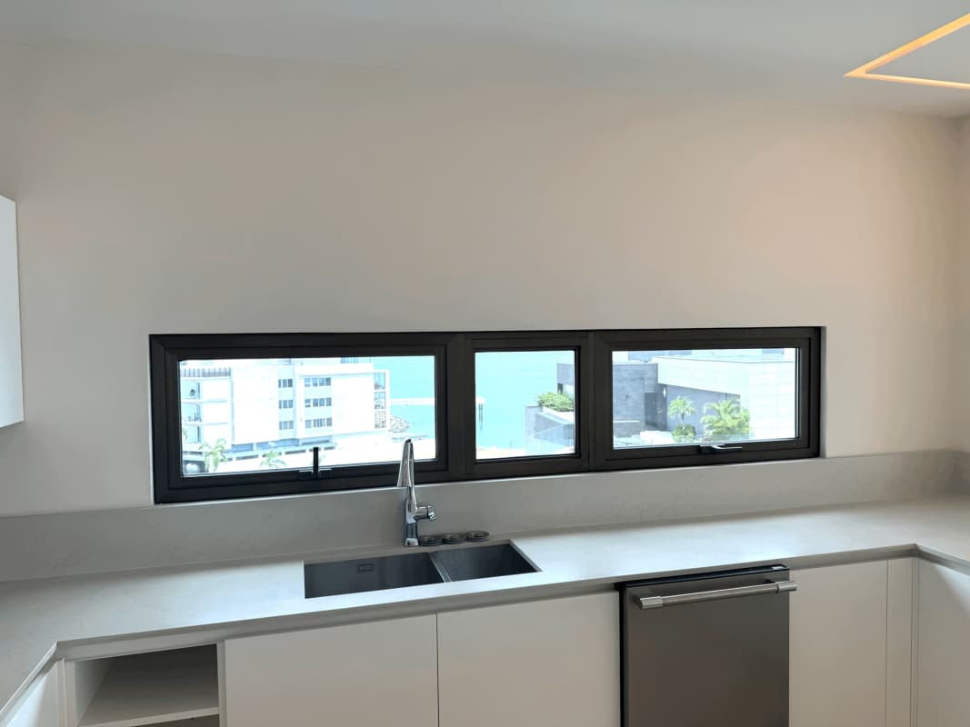 Contemporary kitchen with large horizontal window, island, luxury finishes overlooking ocean at Seascape