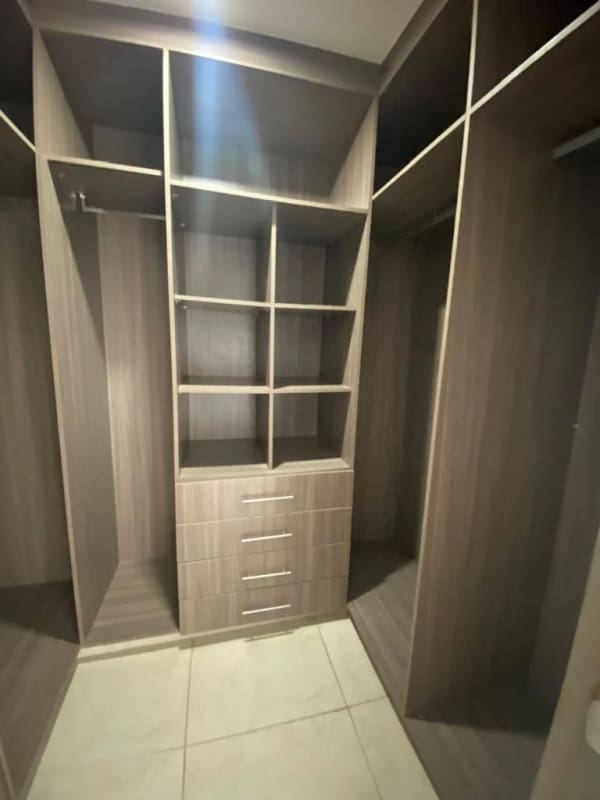 Modern walk-in closet with built-in cabinetry drawers hanging rods at PH Lumiere Costa del Este Panama