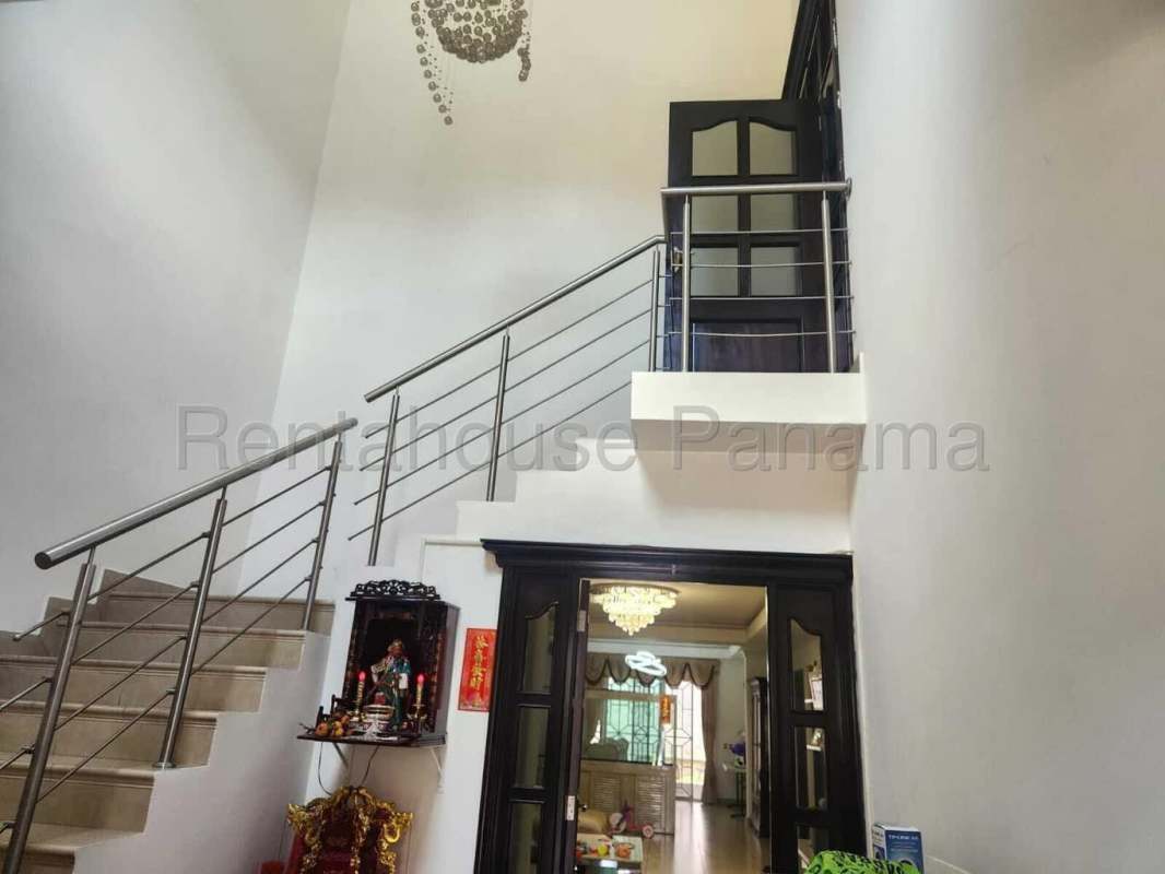Spacious living room with high ceiling chandelier and staircase Dorado Village Panama