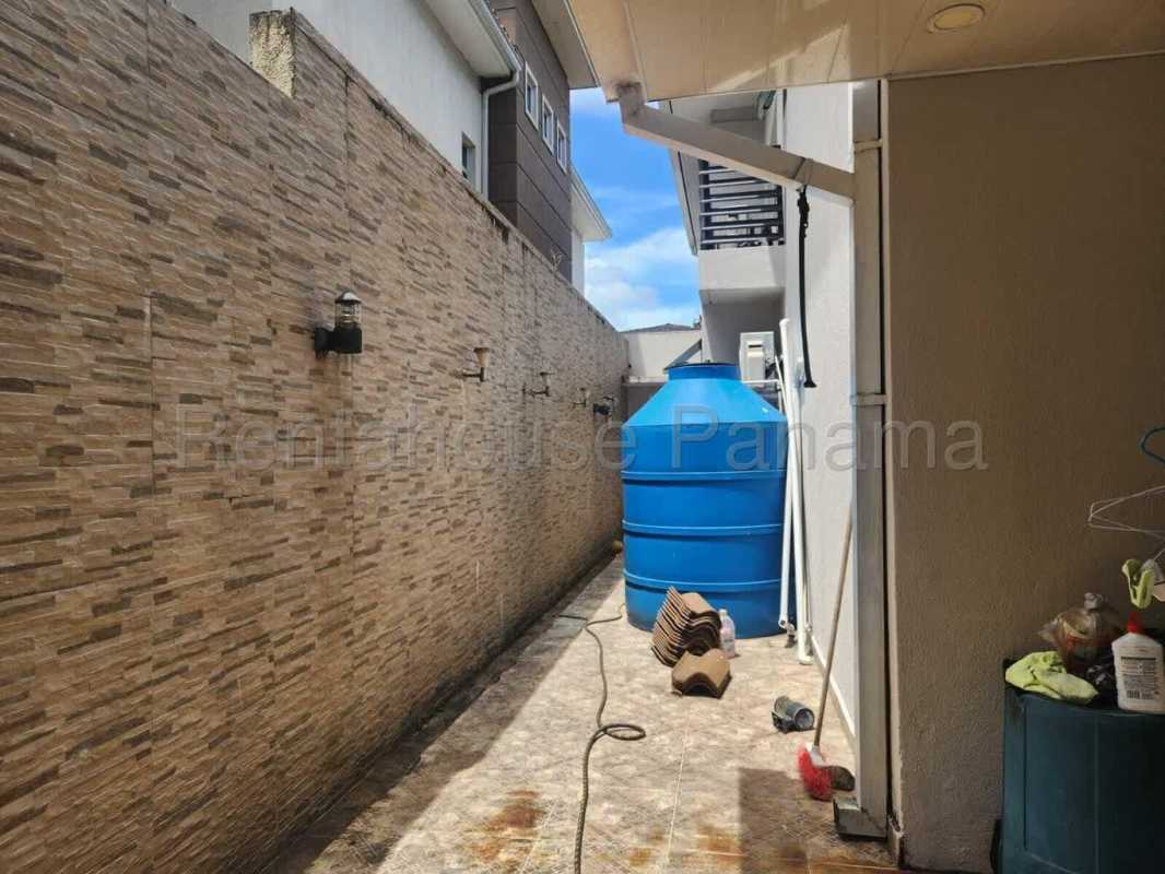 Side outdoor utility corridor with blue water tank at Dorado Village Panama