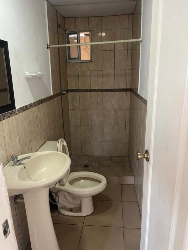Small bathroom tiled with pedestal sink, toilet and shower in Paraíso San Miguelito apartment Panama