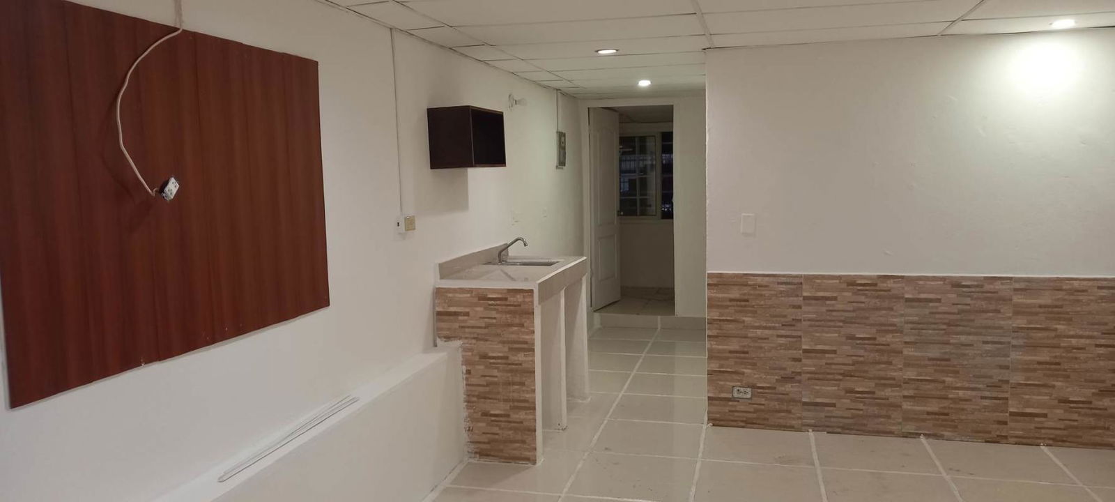 Small kitchenette with beige tiles and cabinetry in Colonias del Prado apartment Panama