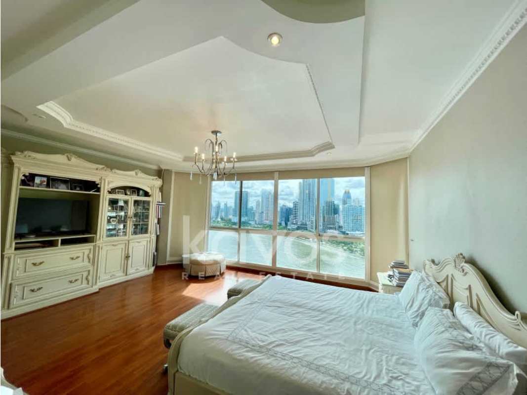 Large master bedroom with wooden floors, city skyline view, and chandelier at PH Peninsula Punta Paitilla Panama