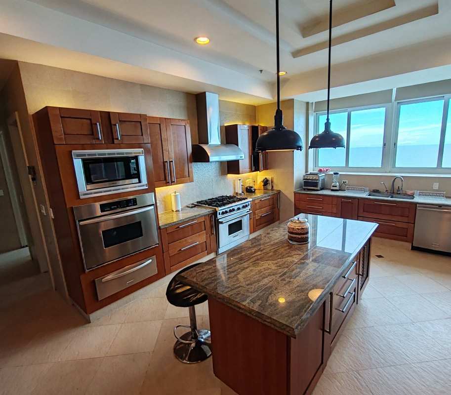 Contemporary luxury kitchen with wood cabinetry, granite island and stainless appliances with ocean views in Punta Paitilla penthouse