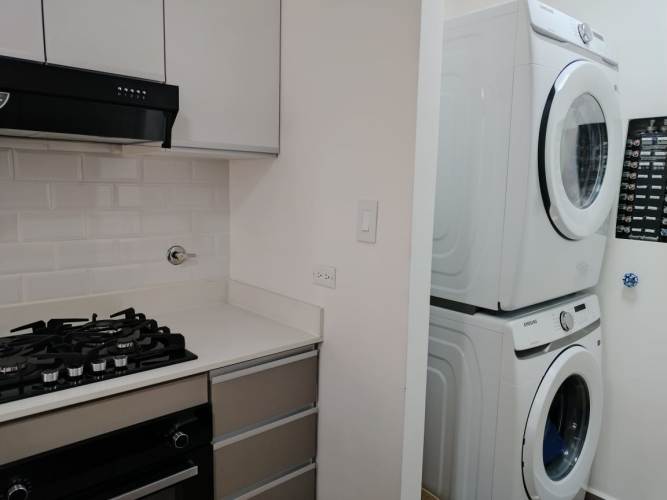 L-shaped modern kitchen with washer dryer and white cabinetry PH Sky Swiss