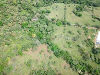 Rural farmland for sale with greenhouses, open fields, mountain backdrop near Punta Chame