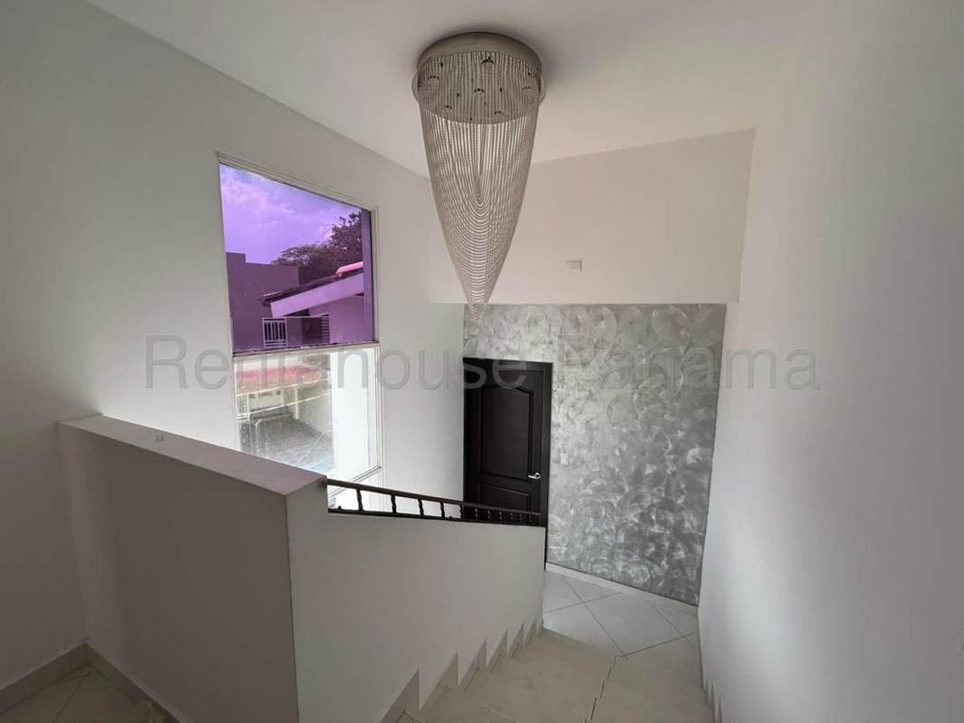 Modern staircase with decorative accent wall and chandelier in rental house Altos de Santa María Panama