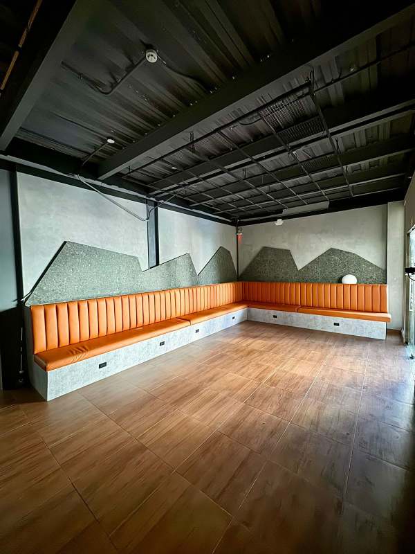 Orange upholstered bench seating wood tile floors exposed ceiling commercial plaza Panama