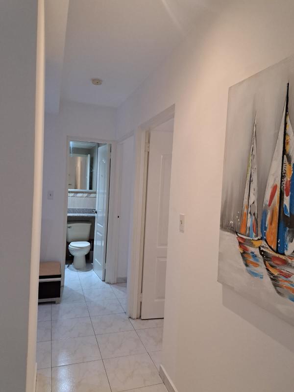 Bright corridor with white tile flooring, wall art and access to bedrooms in PH Clayton Tower Panama