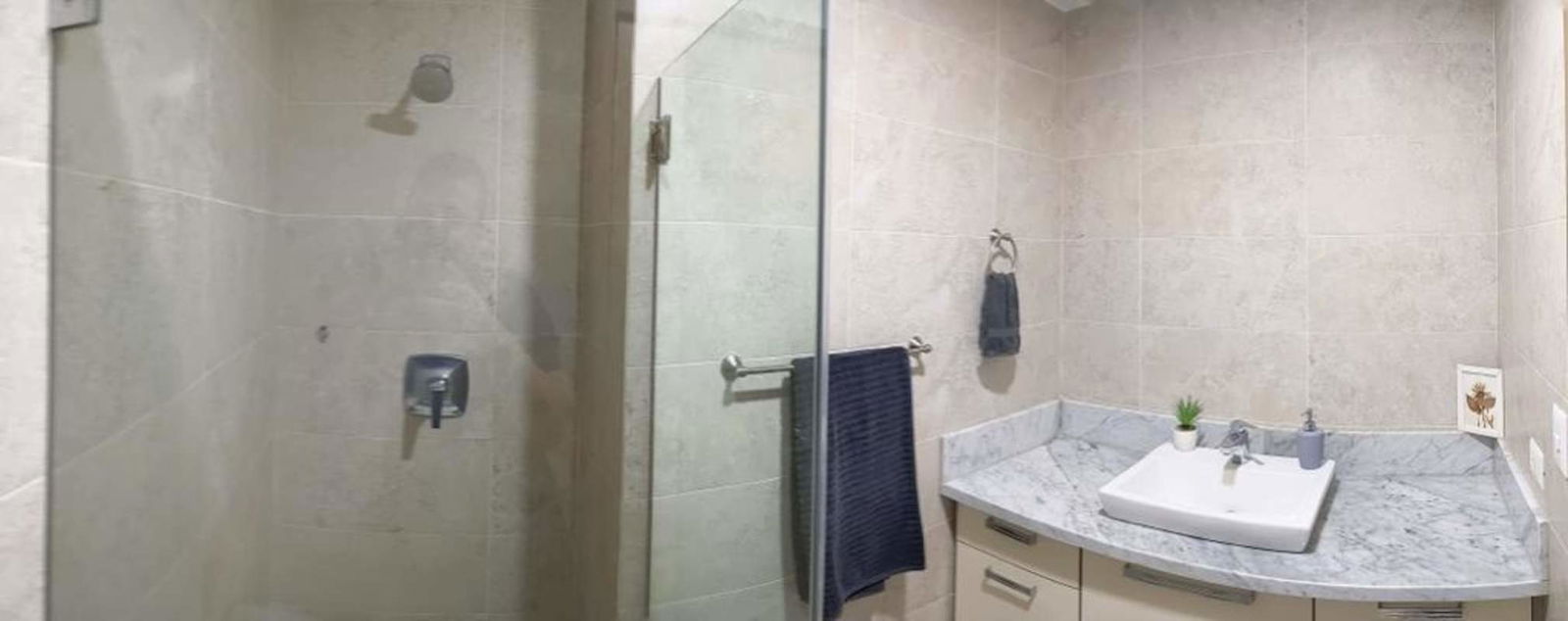 Modern bathroom with glass enclosed shower and marble countertop apartment rental