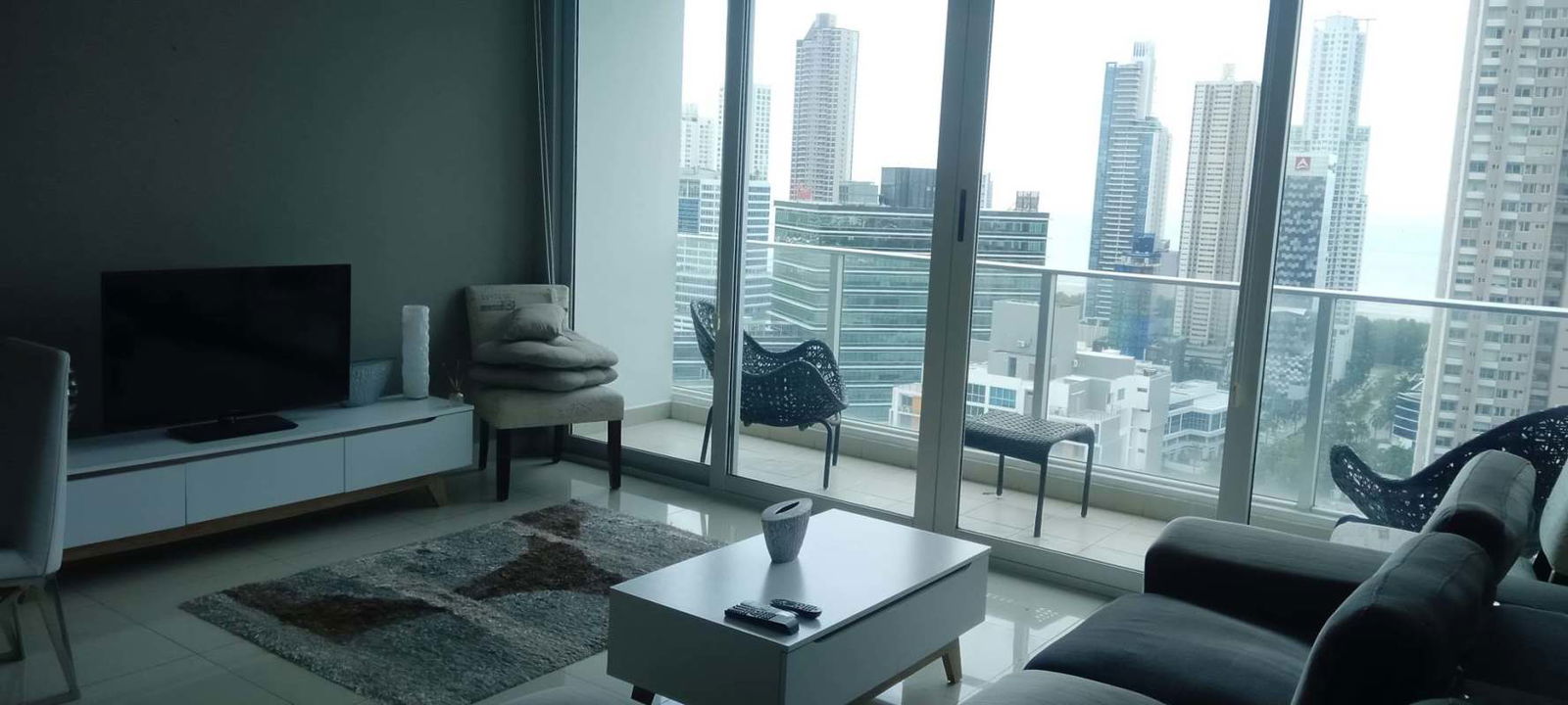 Living room with panoramic city skyline views and balcony in PH Riverside Costa del Este Panama City