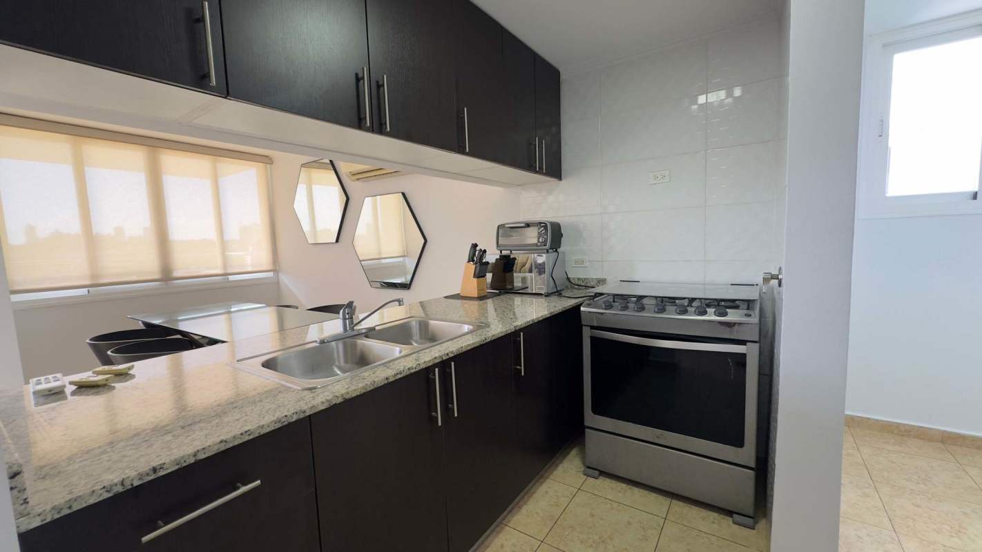 Kitchen with granite counters, dark cabinets and appliances in Elevation Tower 12 de Octubre Panama