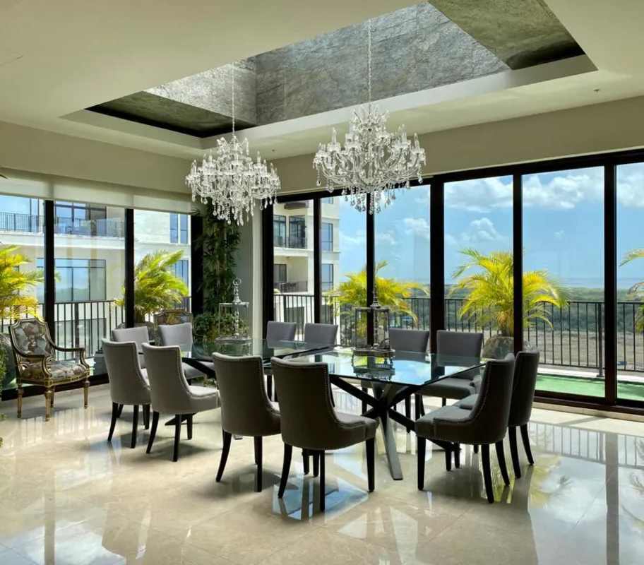 Modern dining room with chandeliers and panoramic windows in luxury penthouse at Santa Maria Panama