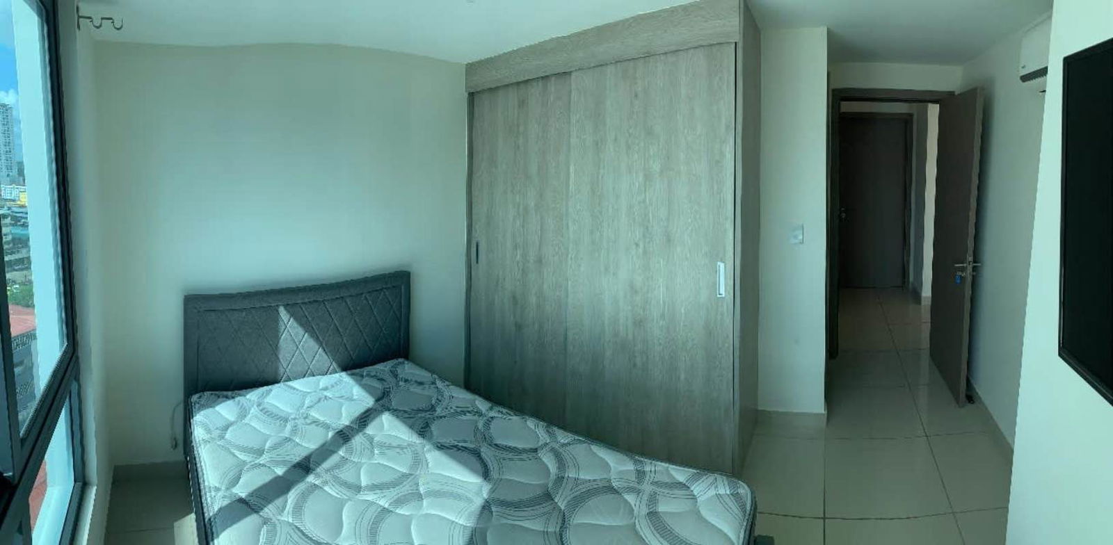 Minimalist bedroom with large window and wardrobe at PH Epoca Panama City