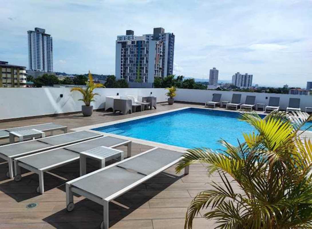 Modern rooftop swimming pool with lounge chairs overlooking Panama City skyline