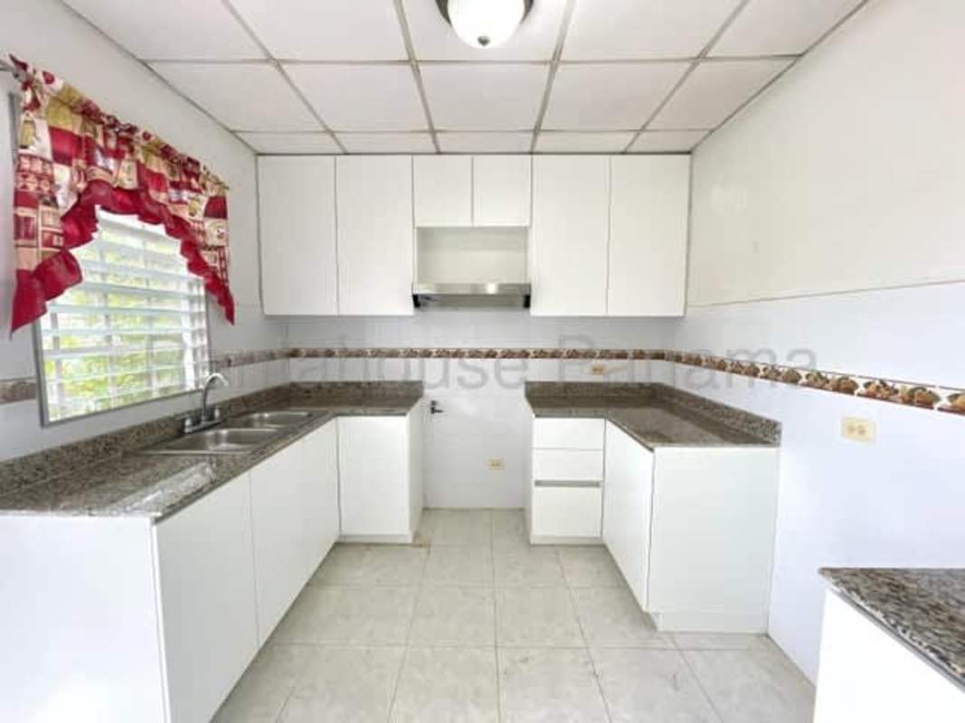 Rental house kitchen with white cabinetry, granite counters, and sink in Altos de las Praderas San Antonio Panama