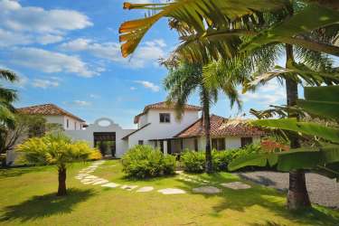 Elegant dining space with high ceiling, colorful chairs, and natural light in Pedasi beachfront villa