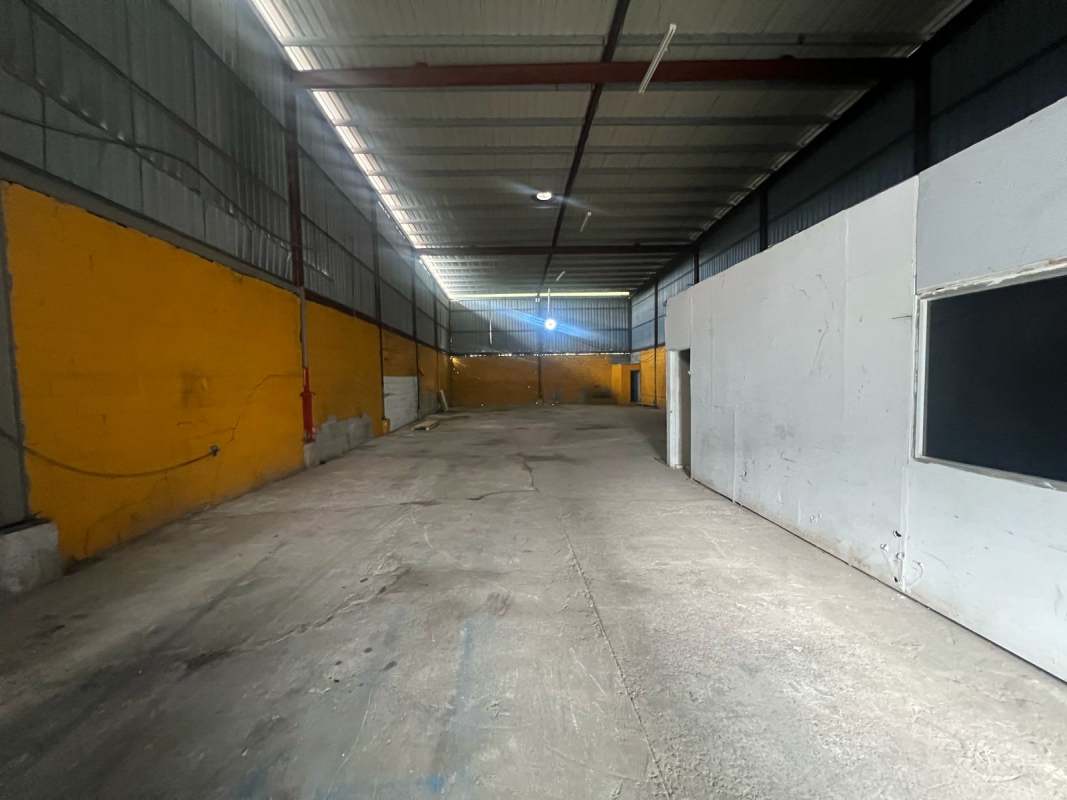 Large empty warehouse with concrete floor, high metal roof, and partitioned wall Las Mañanitas Panama