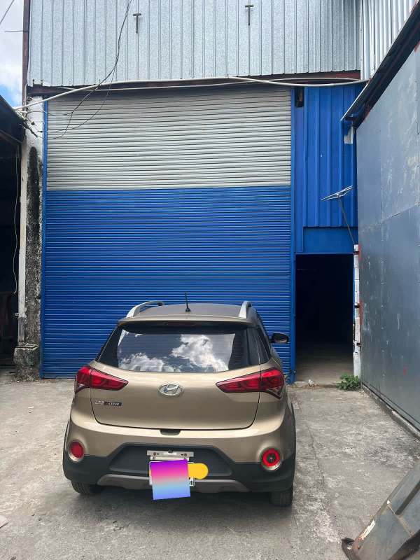 Exterior view warehouse with blue metal rolling door and concrete driveway in Las Mañanitas Panama