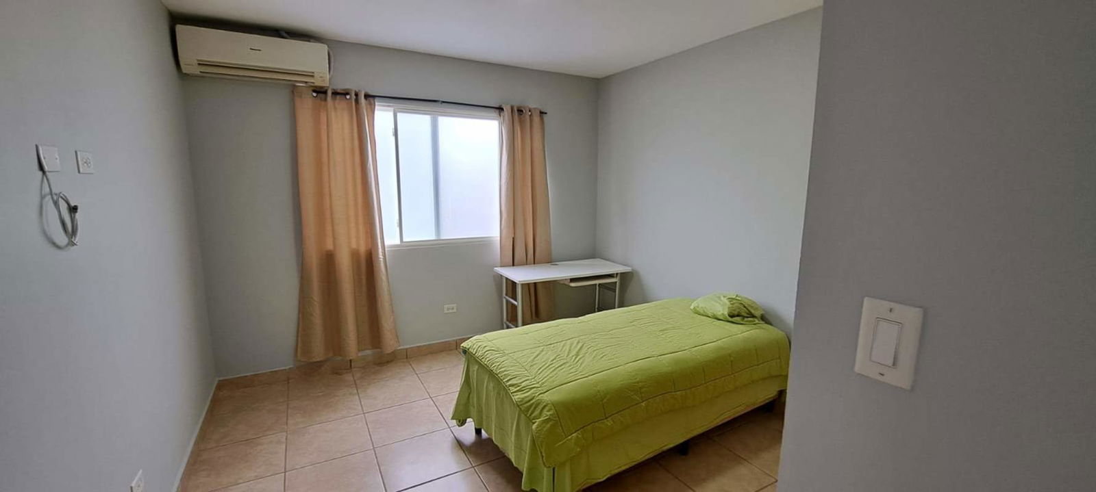 Minimalist bedroom with green bedding, split AC, closet and tile floor PH Alpes Panama City