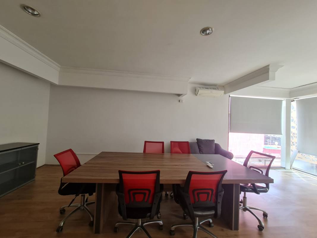 Modern conference room with large table, red chairs, wood floors, bright windows PH Obarrio Center Panama