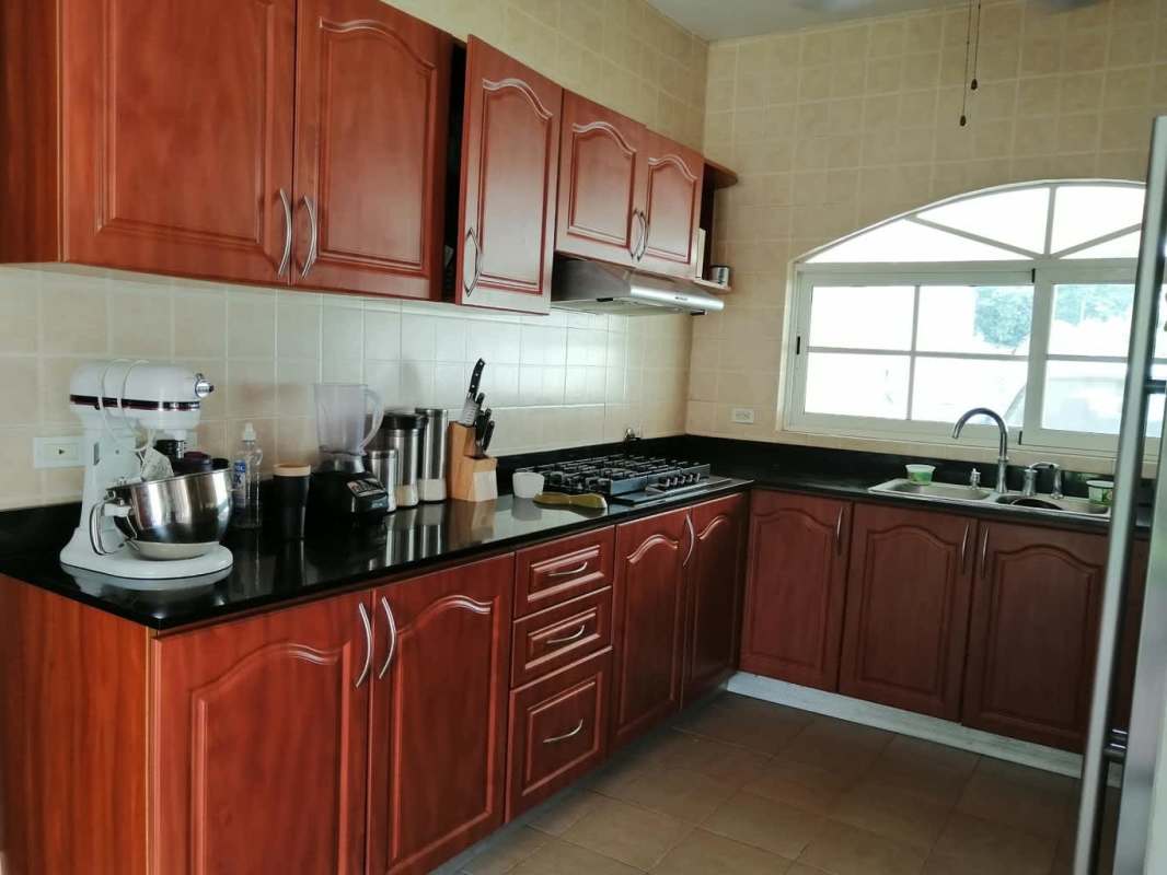 Spacious kitchen with wooden cabinetry, granite counters, arched window, gas stove PH Green Field Panama