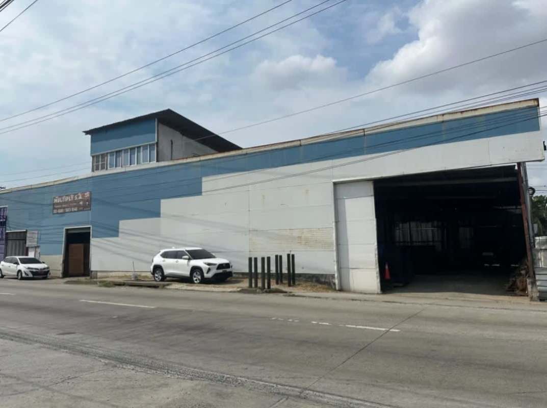 Exterior industrial warehouse facade with rolling door and parking in Llano Bonito Panama