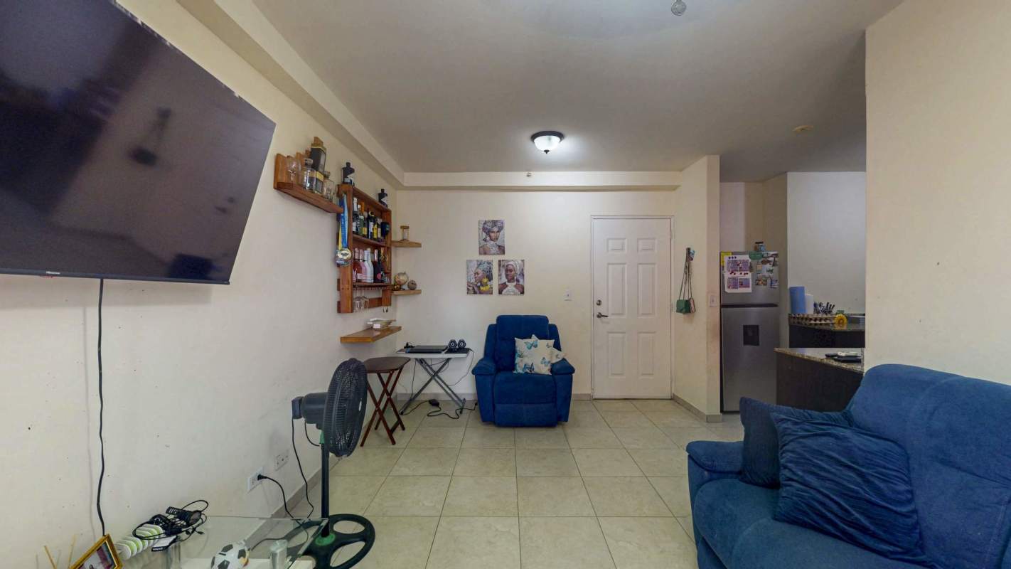 Living space with blue sofa set and TV, open to kitchen and balcony PH El Doral Panama City