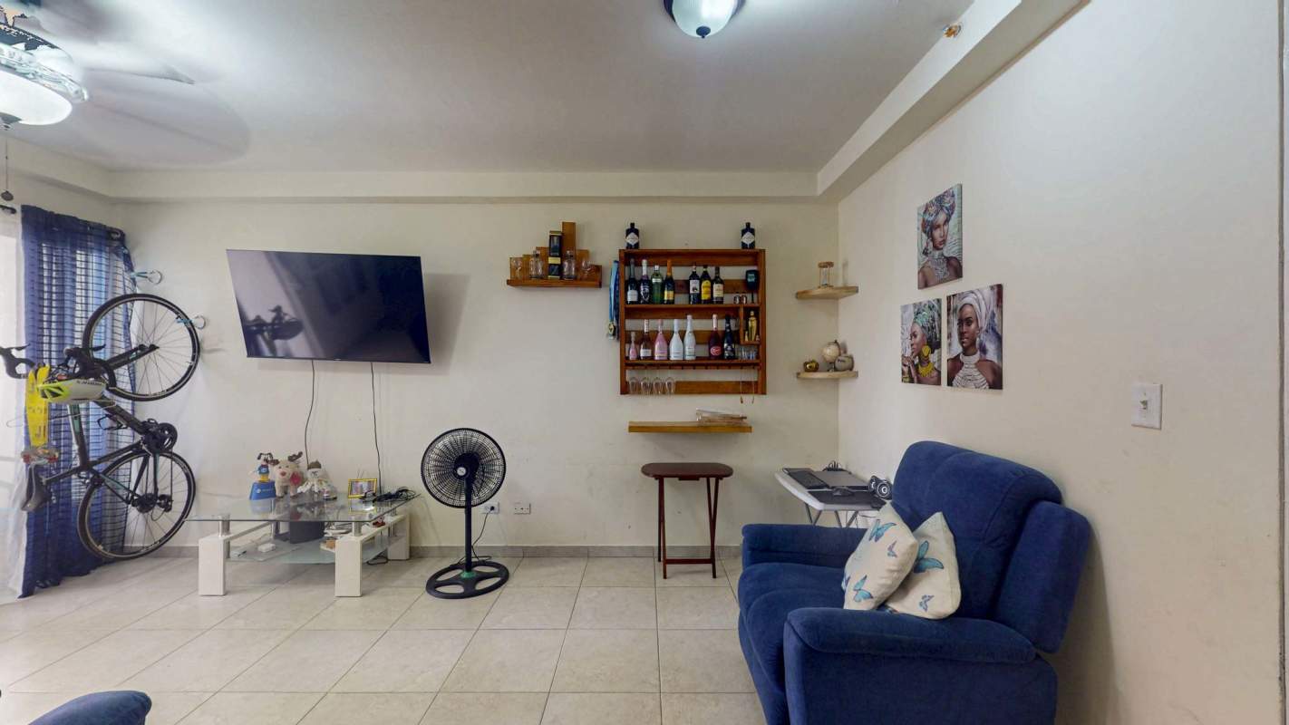 Furnished living space with wall-mounted TV, blue armchair, and decorative accents PH El Doral Hato Pintado Panama