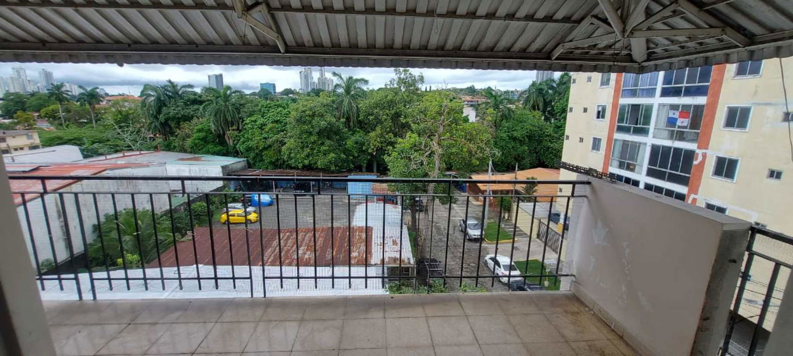 Covered apartment balcony with tile floor and metal railing overlooking Panama City