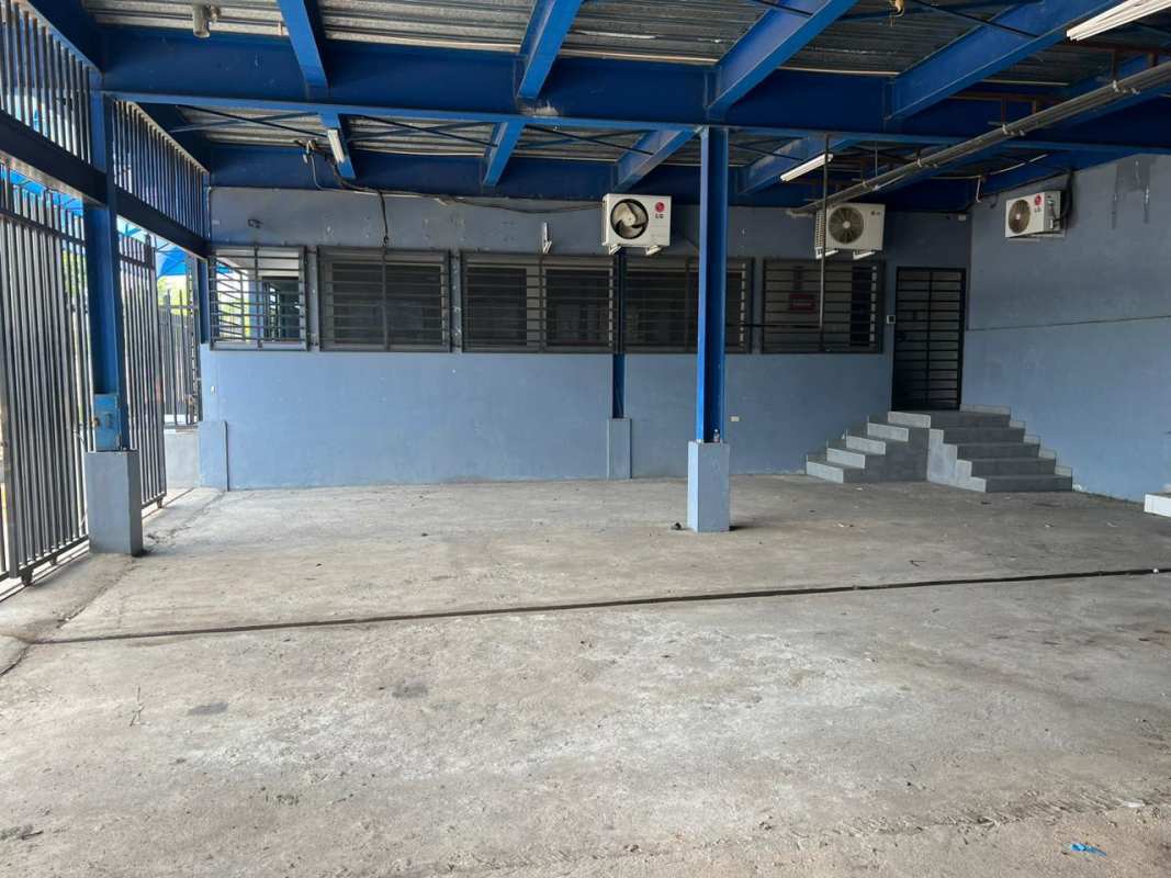 Covered loading zone with concrete surface, metal roof beams, secured entry in industrial complex