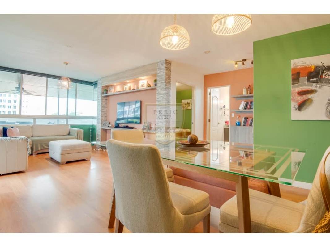 Dining room with green accent wall, pendant lighting and wood floors at PH Cangrejo 507 Panama City