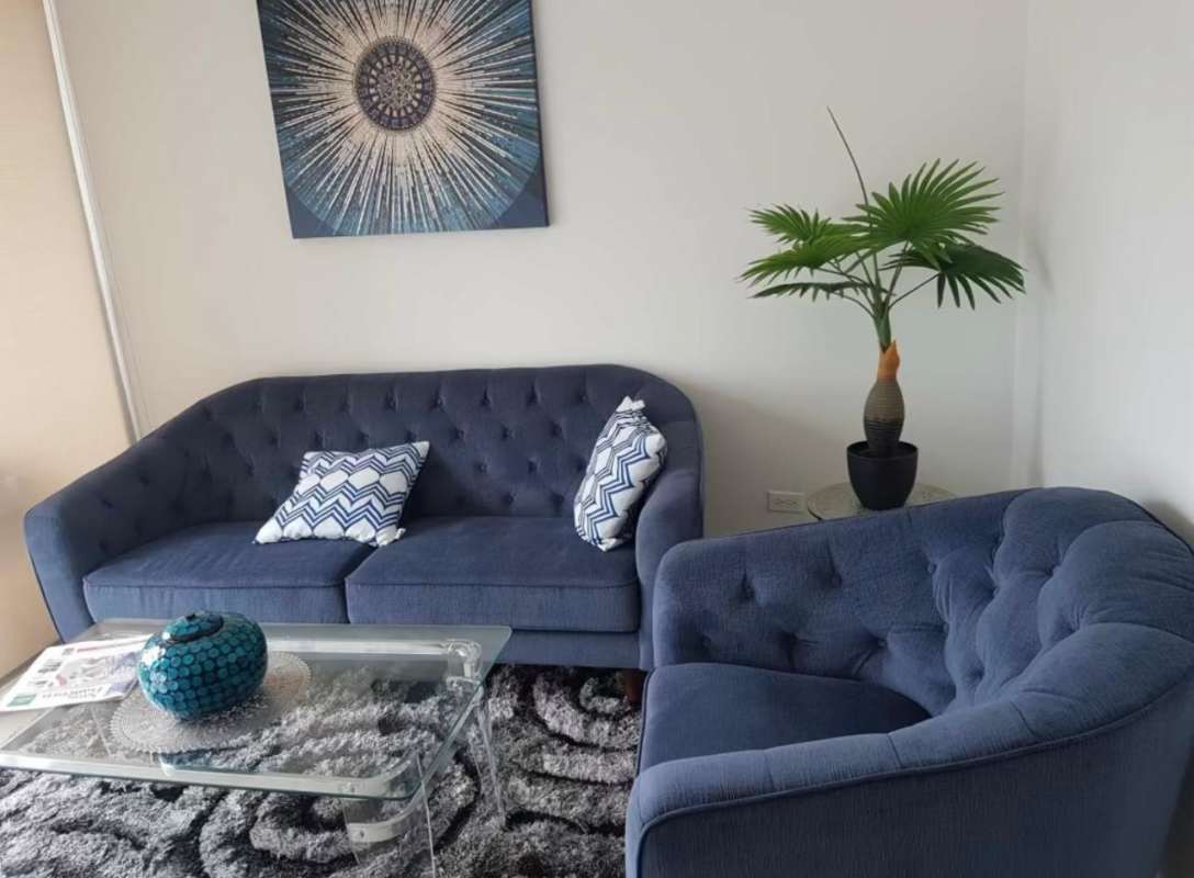 Modern living space with blue sofa, abstract art and large windows at PH Sky Park Carrasquilla Panama